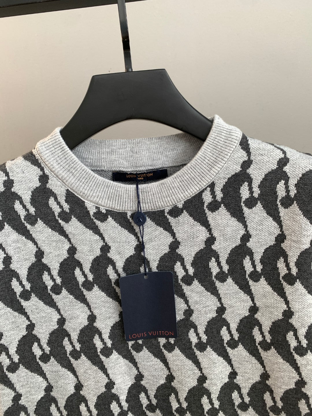 White and black patterned knit sweater close-up, ribbed crew neck, hanging brand tag
