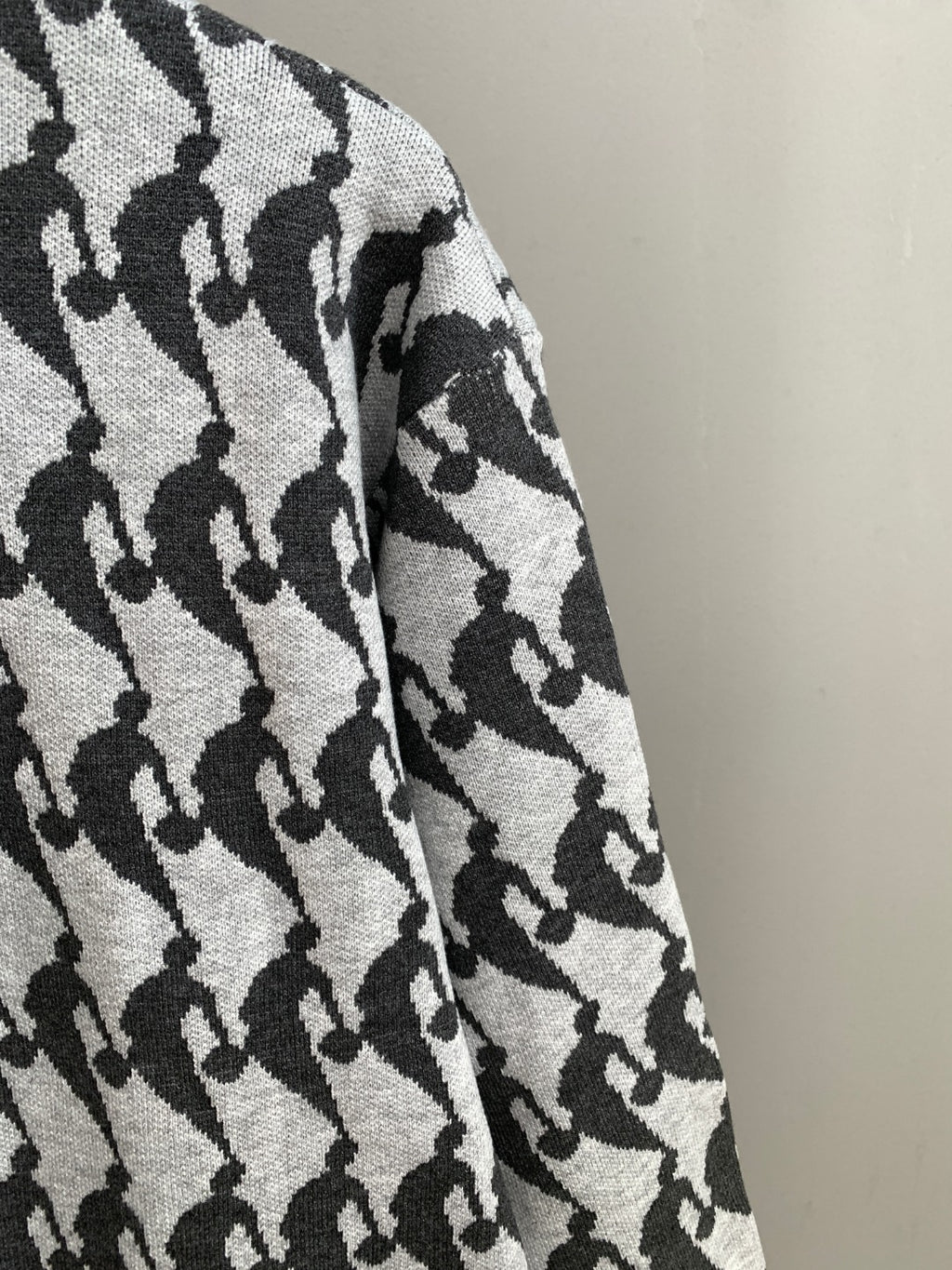 Sleeve section of long-sleeve sweater in light knit with black silhouette pattern