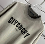 Givenchy T-shirt close-up: “GIVENCHY” print with “PARIS” below, sage gray