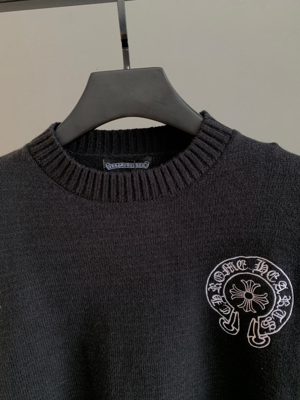 Charcoal knit sweater with ribbed crew neck and circular front logo emblem