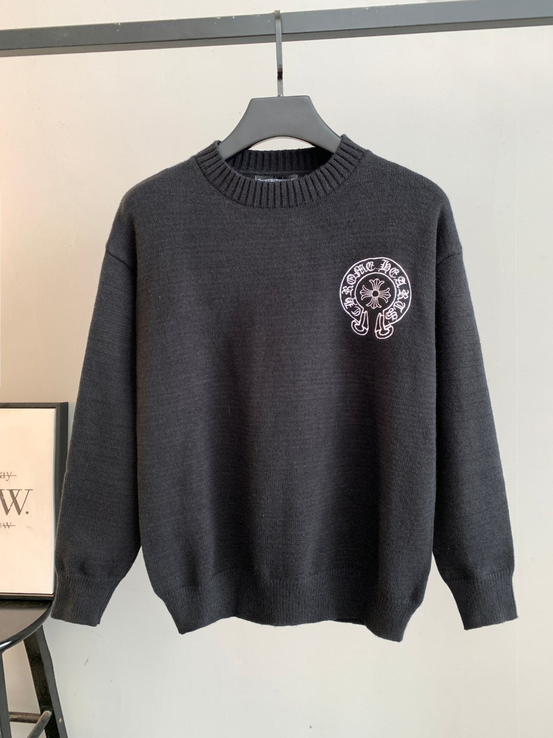 Charcoal knit long-sleeve sweater with ribbed crew neck and small front logo patch