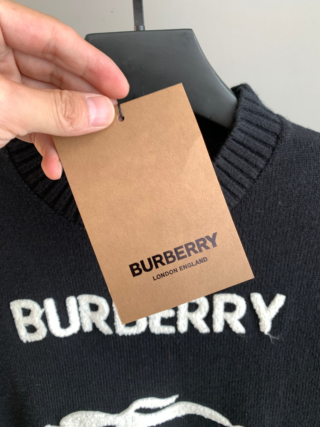 Burberry sweater close-up with attached hang tag and BURBERRY text near logo