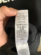 Clothing care label inside dark knit sweater, held in hand