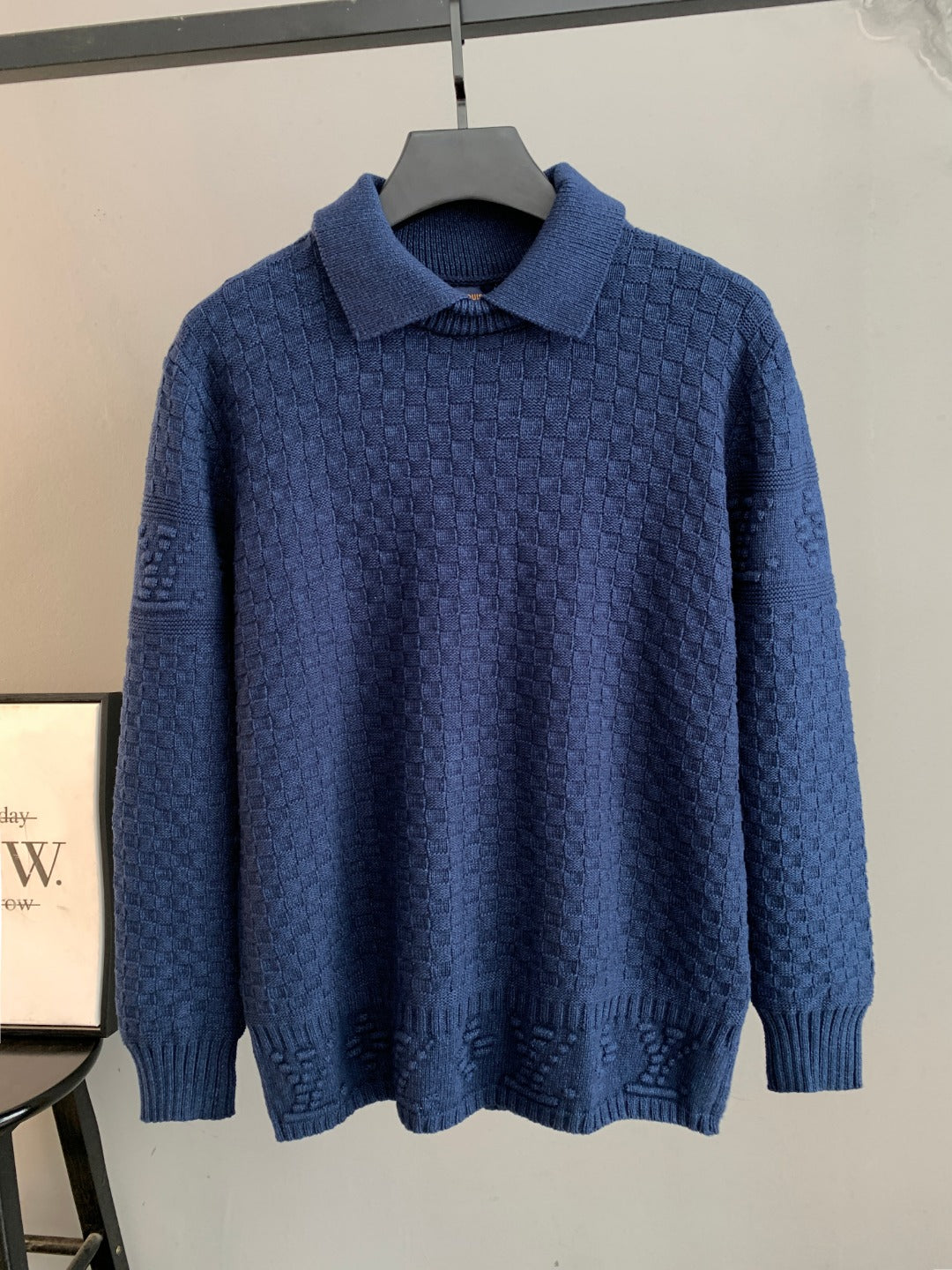 Blue knit sweater with point collar and long sleeves on hanger
