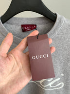 Grey sweatshirt neckline with red Gucci label and hanging tag