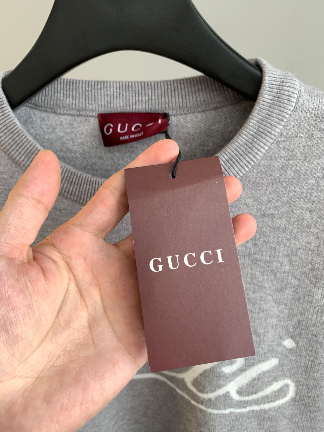 Grey sweatshirt neckline with red Gucci label and hanging tag