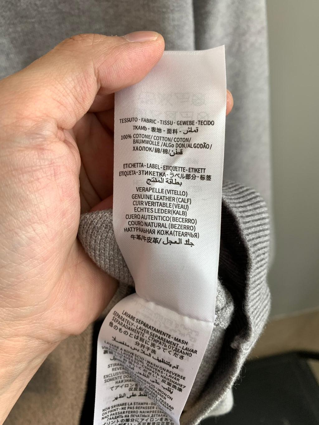 Grey sweatshirt inner care label in hand