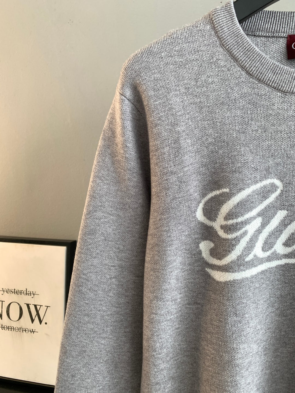 Grey knit sweatshirt sleeve with partial Gucci script logo