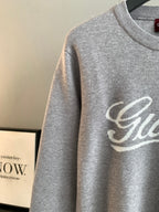 Grey knit sweatshirt sleeve with partial Gucci script logo