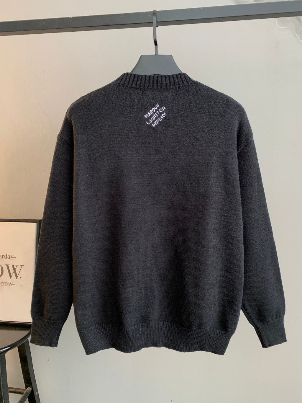 Charcoal knit crewneck sweater back with small embroidered white text