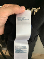 Black knit sweater care label showing 100% cotton fabric information