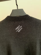 Charcoal knit sweater back with embroidered white text centered