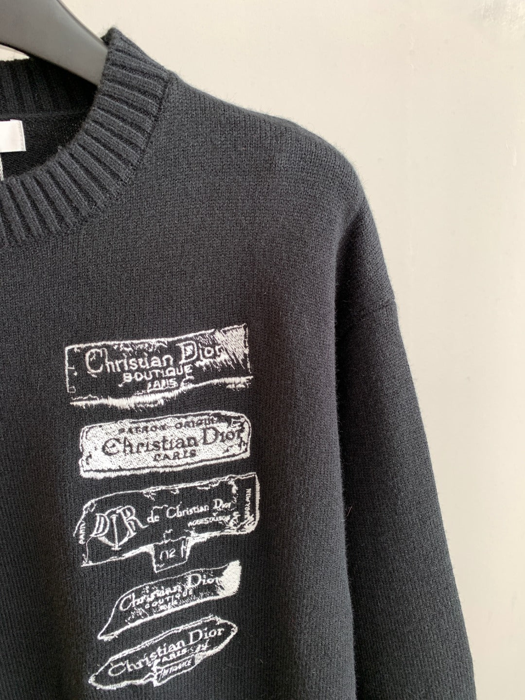 Dark knit sweater with stacked Christian Dior logo patches on the chest