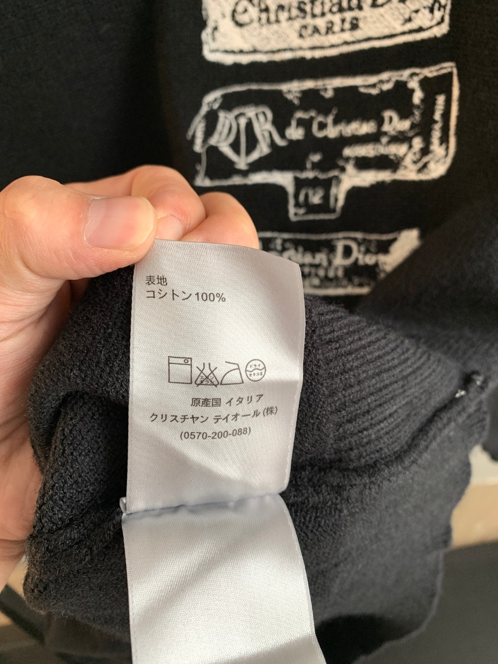 Dark knit sweater care label showing 100% cotton and wash instructions