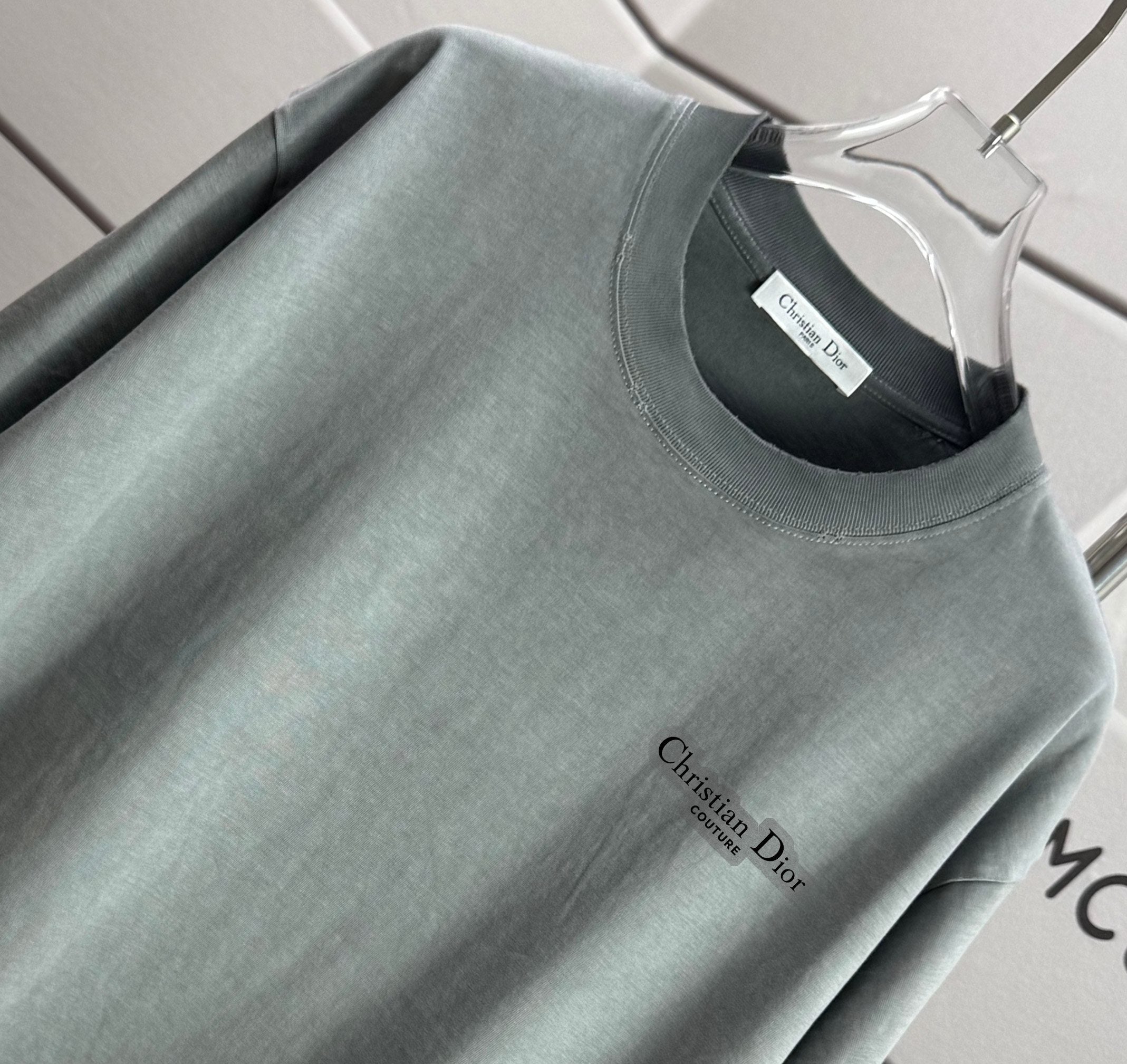 Light gray short-sleeve T-shirt close-up: crew neck and Christian Dior logo detail.