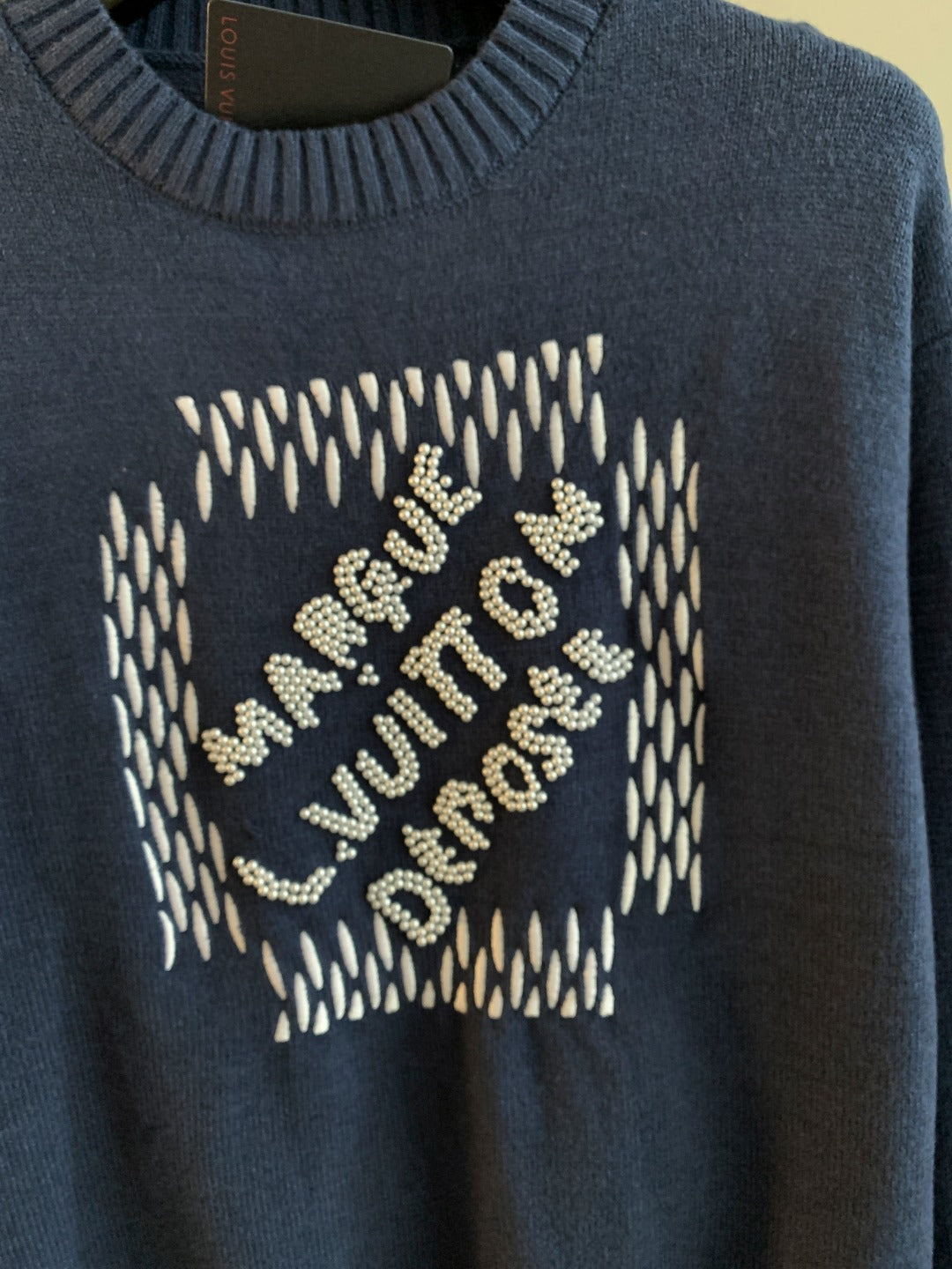 Navy blue knit sweater front with beaded letters graphic