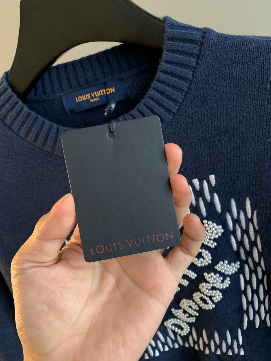 Navy blue knit crewneck sweater with Louis Vuitton hang tag near neckline