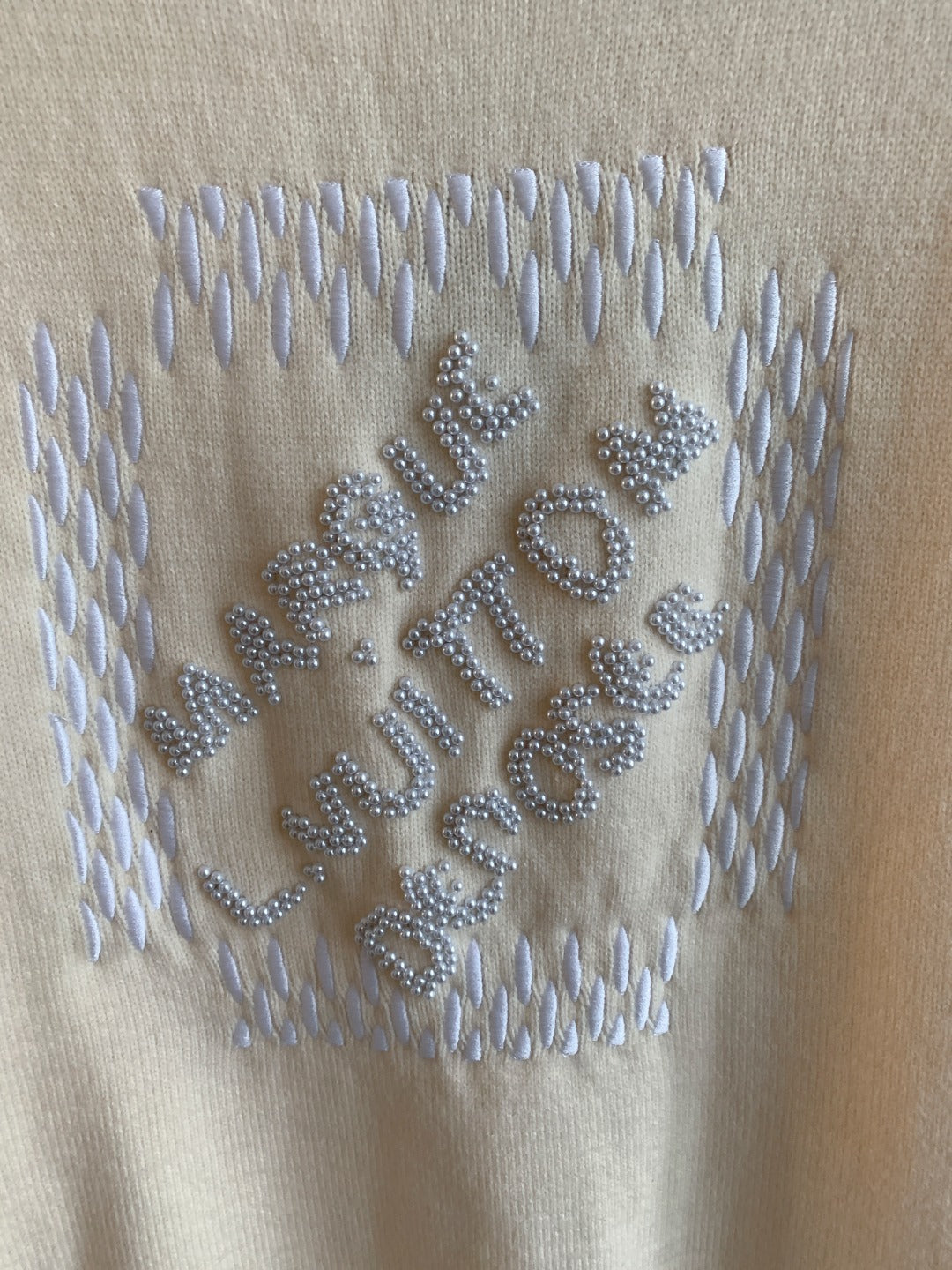 Cream knit sweater with raised rhinestone Louis Vuitton lettering across the chest