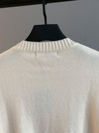 Cream knit crewneck sweater back view with ribbed collar on hanger