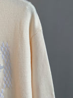 Cream knit sweater sleeve with partial rhinestone logo graphic