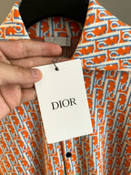 Dior logo-print shirt with hanging tag, orange-and-blue patterned fabric close-up