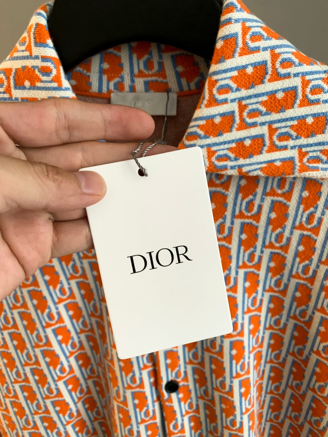 Dior logo-print shirt with hanging tag, orange-and-blue patterned fabric close-up