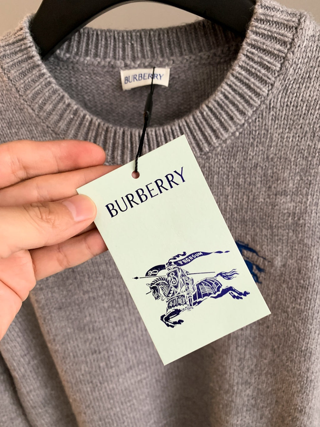 Heather gray knit sweater with ribbed crew neck and hanging Burberry tag