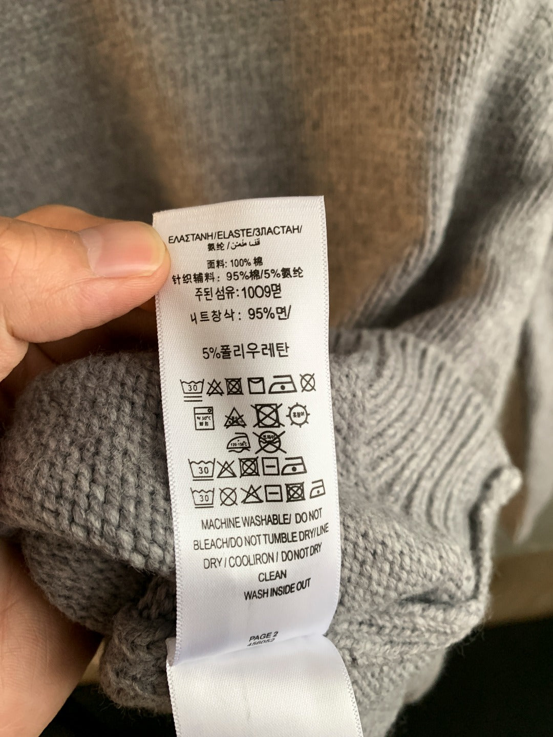 Heather gray knit sweater care label with fabric composition and wash symbols