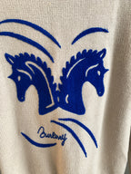 Cream knit sweater with large blue horse heads and arched eye graphic