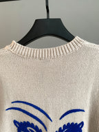 Cream knit sweater with blue arched eyes graphic at upper back