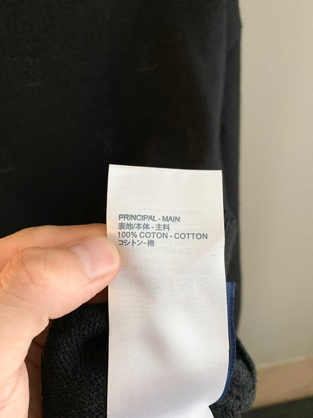 Clothing label tag on dark Louis Vuitton knit sweater: cotton blend text