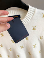 White sweater on hanger with Louis Vuitton hang tag and gold monogram print