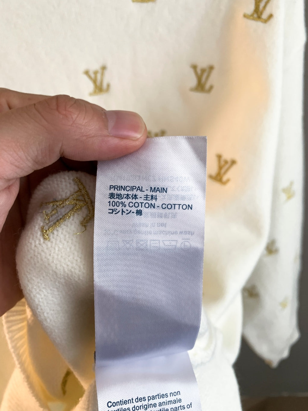White knit sweater care label showing cotton content and parts warning