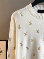 White knit sweater with gold Louis Vuitton monogram pattern, close-up of shoulder and neck