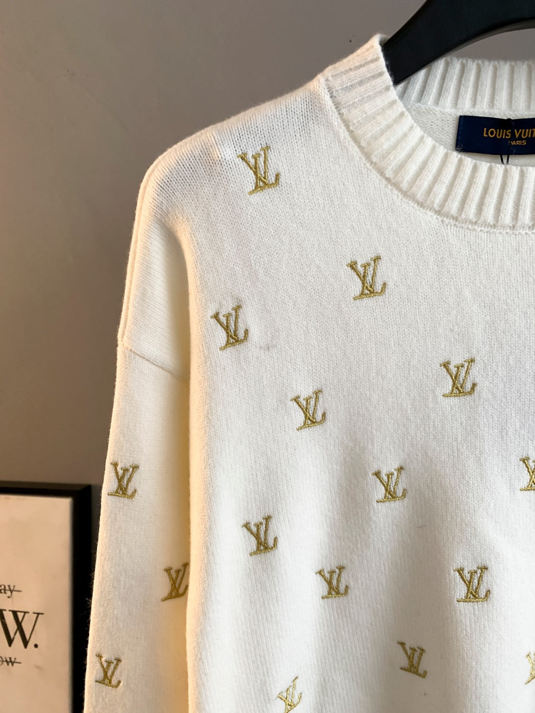 White knit sweater with gold Louis Vuitton monogram pattern, close-up of shoulder and neck