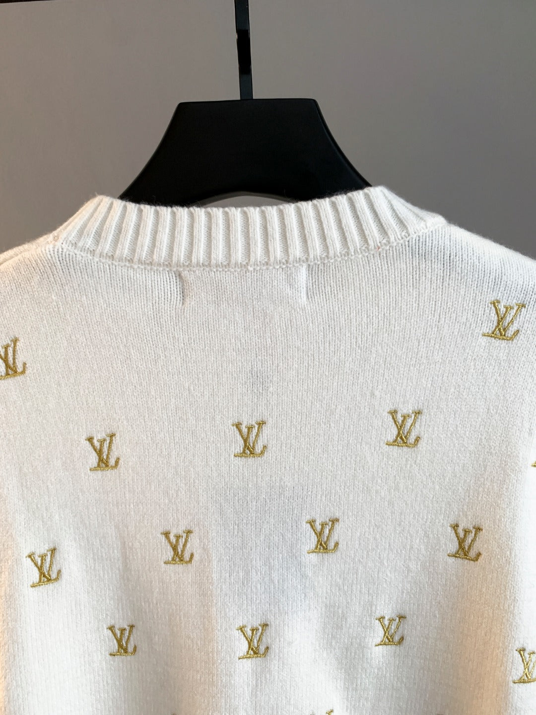 White knit sweater with gold Louis Vuitton monogram pattern, close-up of back yoke