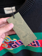 Gucci knit sweater with hanging care tag over green/red stripe logo