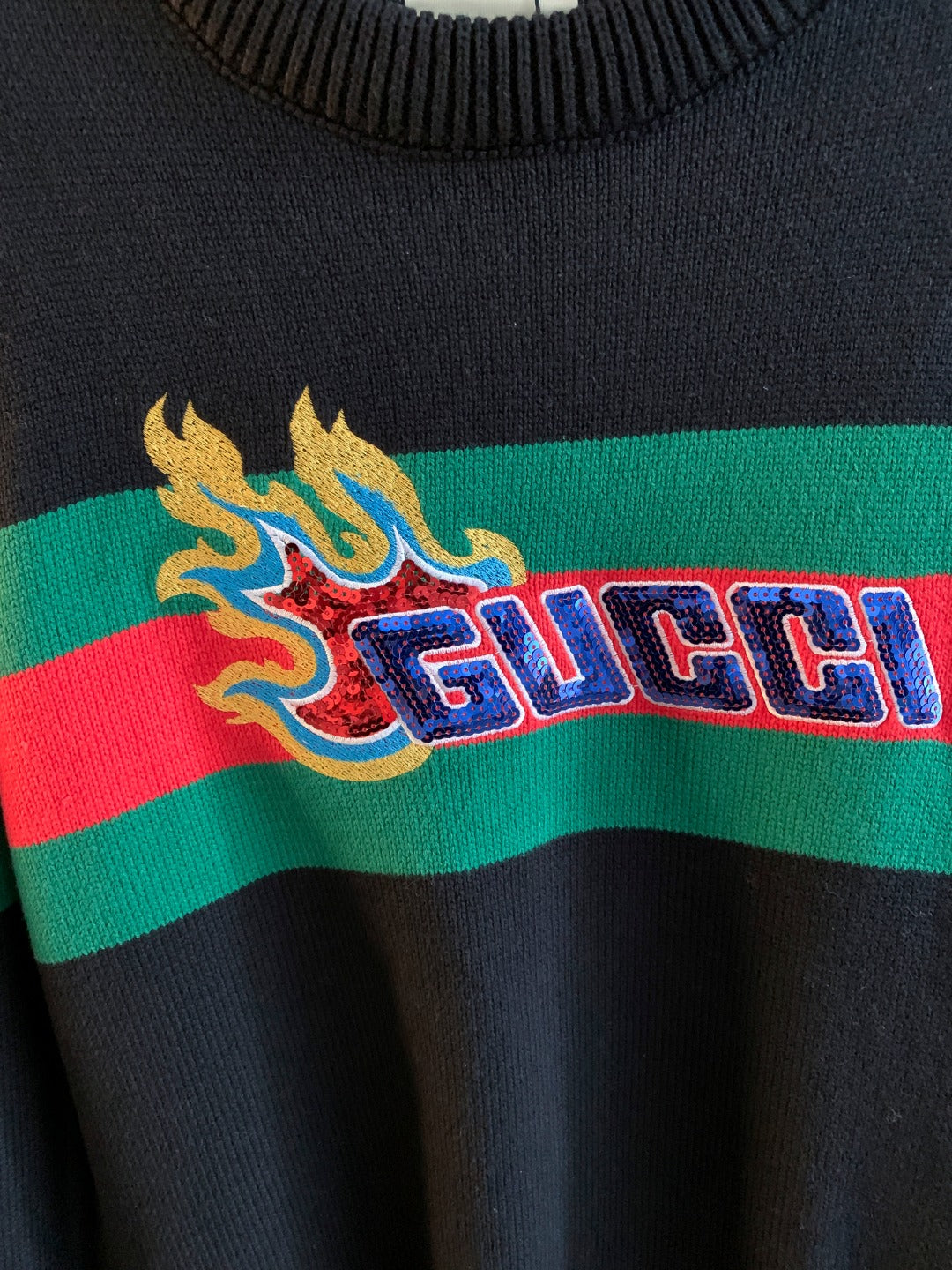 Gucci knit sweater chest graphic with flame and “GUCCI” text on green/red stripe
