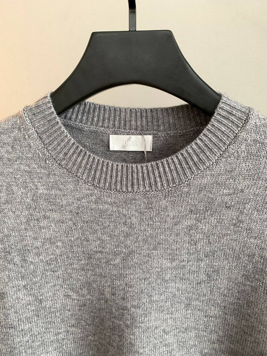 Gray crewneck knit sweater close-up with ribbed collar on hanger