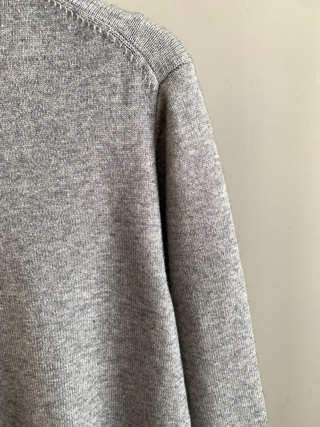 Gray knit sweater side profile with long sleeves and ribbed hem