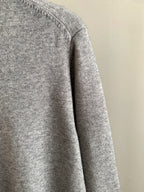 Gray knit sweater side profile with long sleeves and ribbed hem