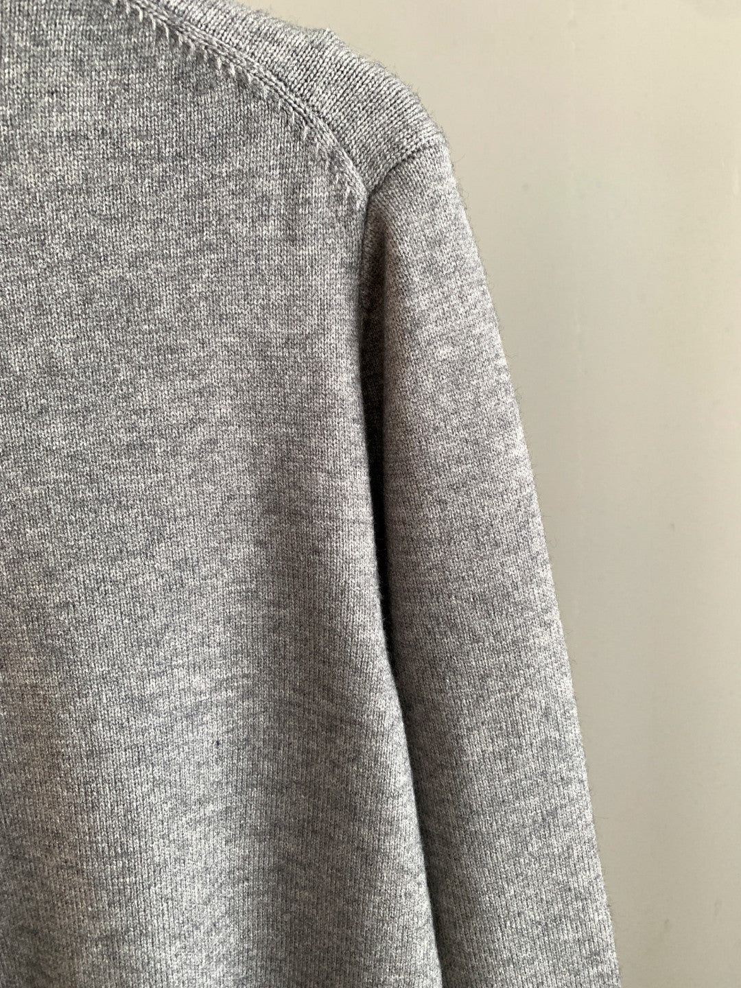 Gray knit sweater side profile with long sleeves and ribbed hem