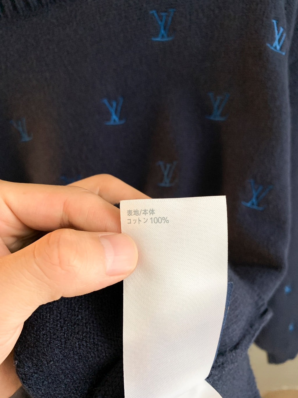 Dark navy knit sweater fabric close-up with care label showing 100% content text