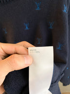 Dark navy knit sweater fabric close-up with care label showing 100% content text