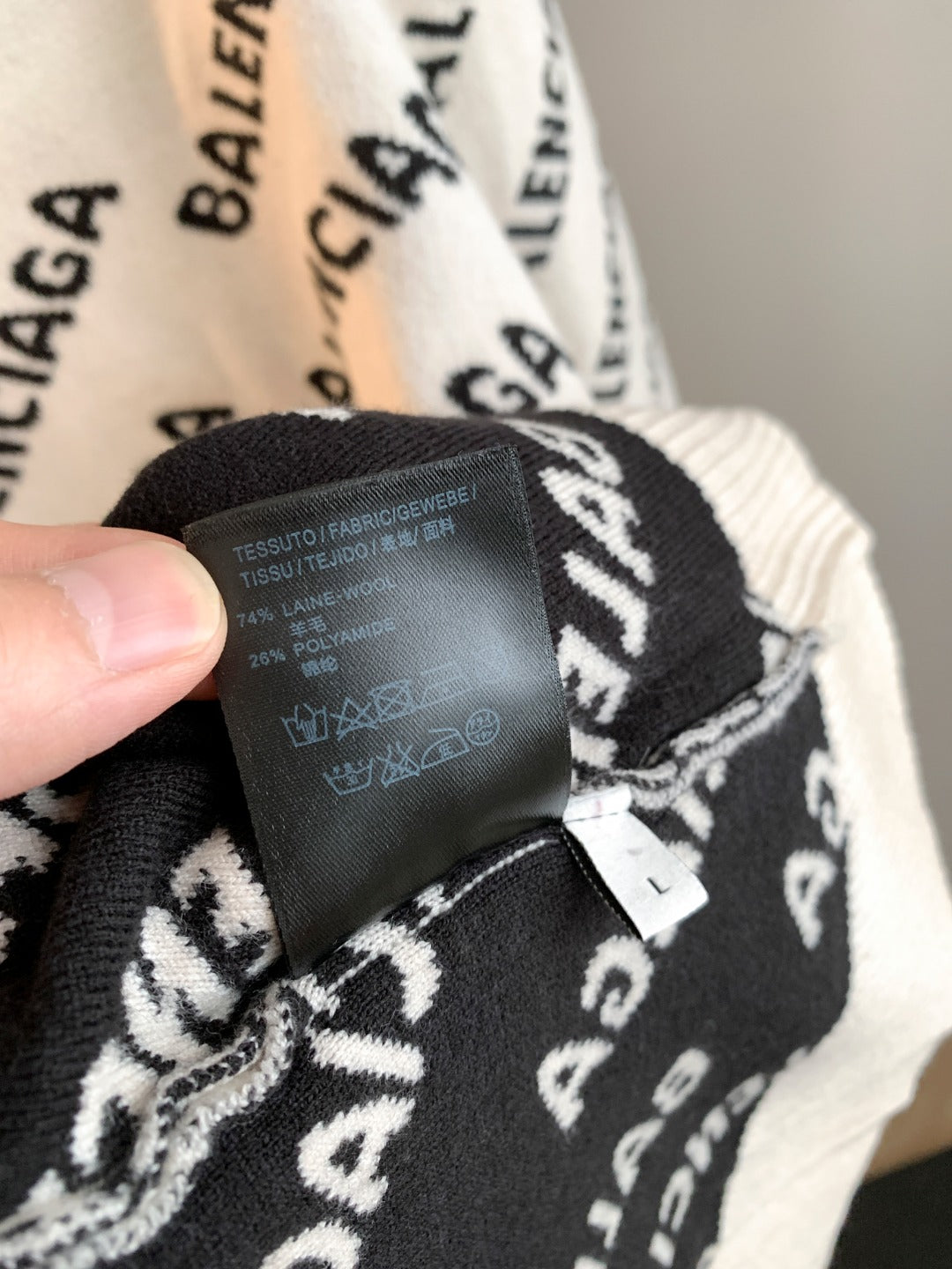 Cream sweater inner collar label and black BALENCIAGA logo pattern; tag detail