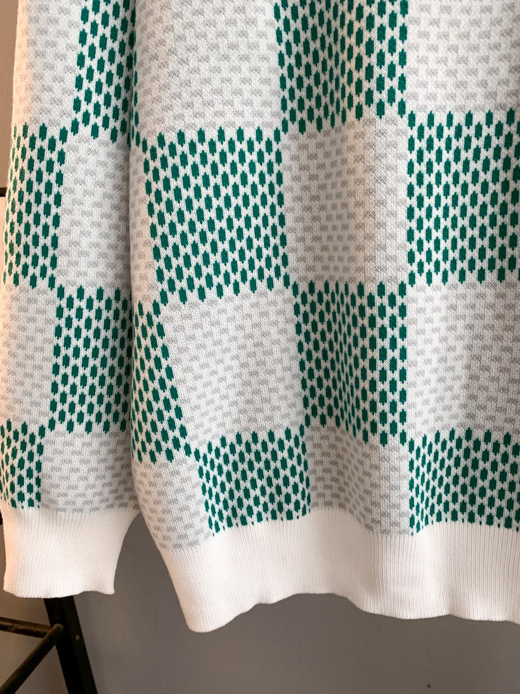 Sweater hem and lower sleeves in white with green check knit pattern