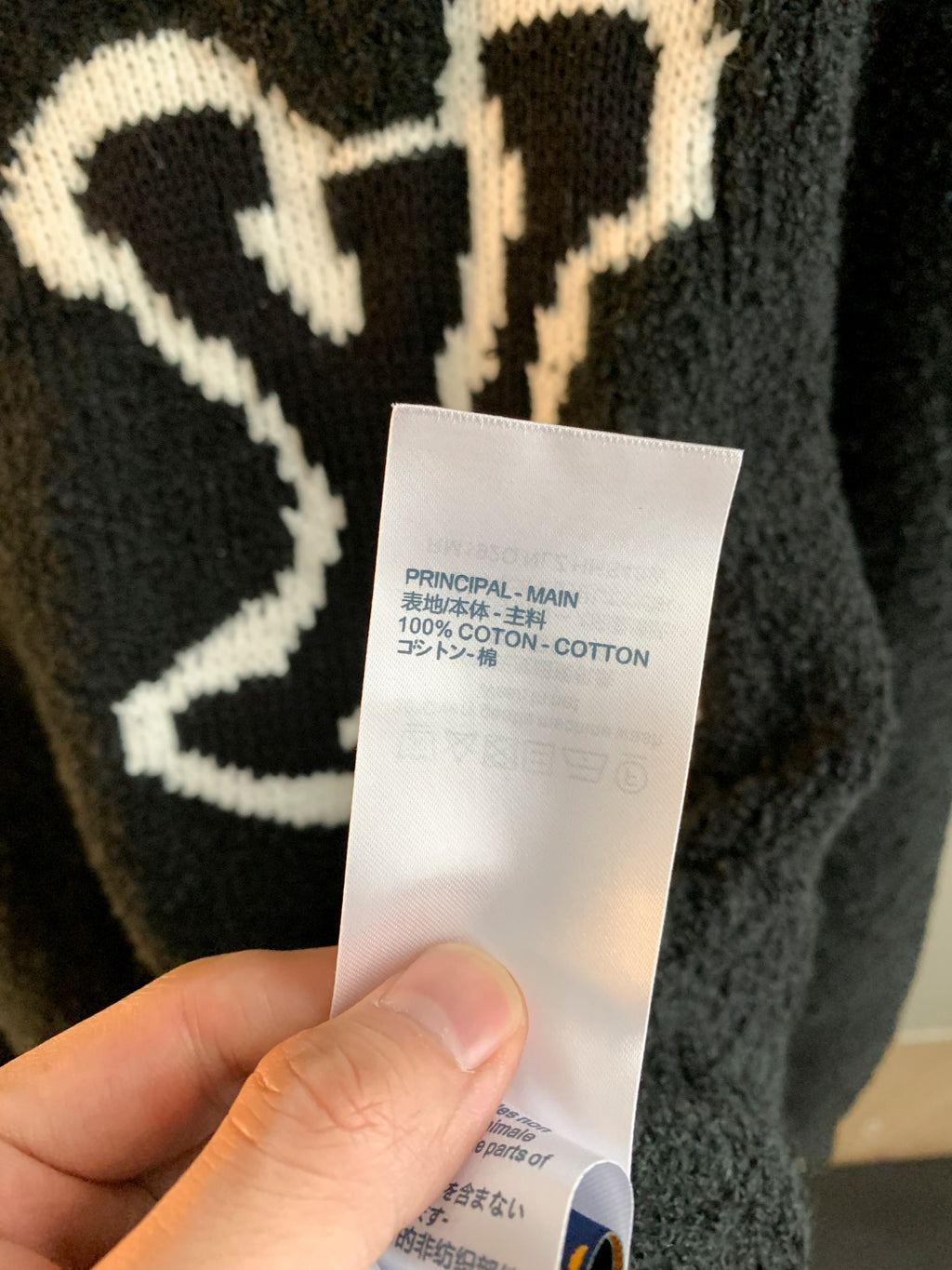 Louis Vuitton sweater care label on white tag attached to dark charcoal knit