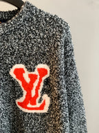 Speckled knit sweater with red logo patch on front, crew neckline visible