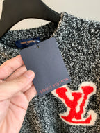 Speckled knit sweater with red logo patch and attached price tag