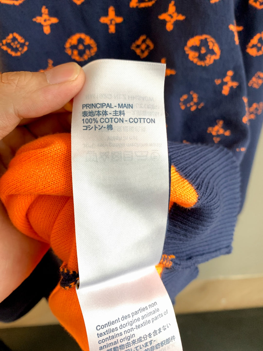 Fabric content label on orange-and-navy monogram sweater